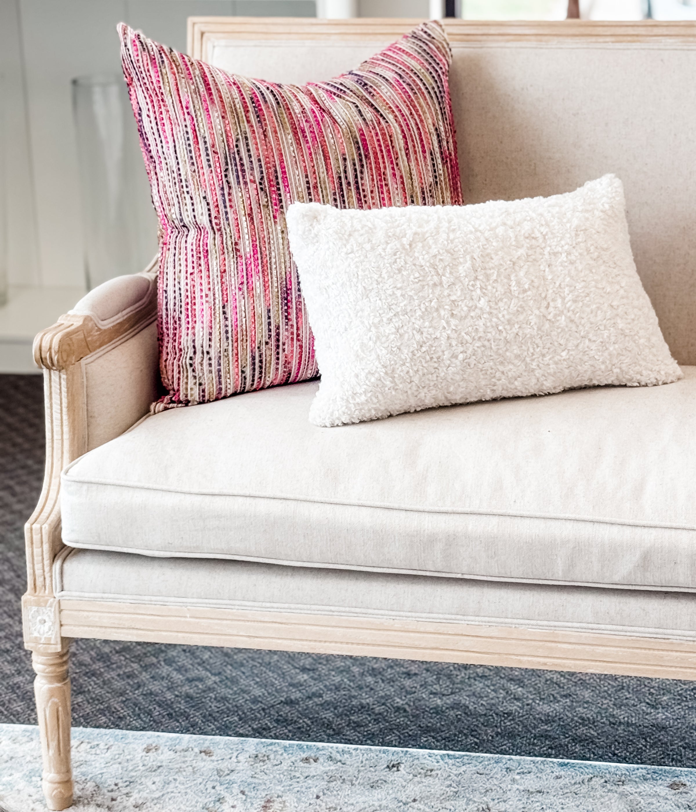 Beige sofa with colorful and white pillows on a neutral background